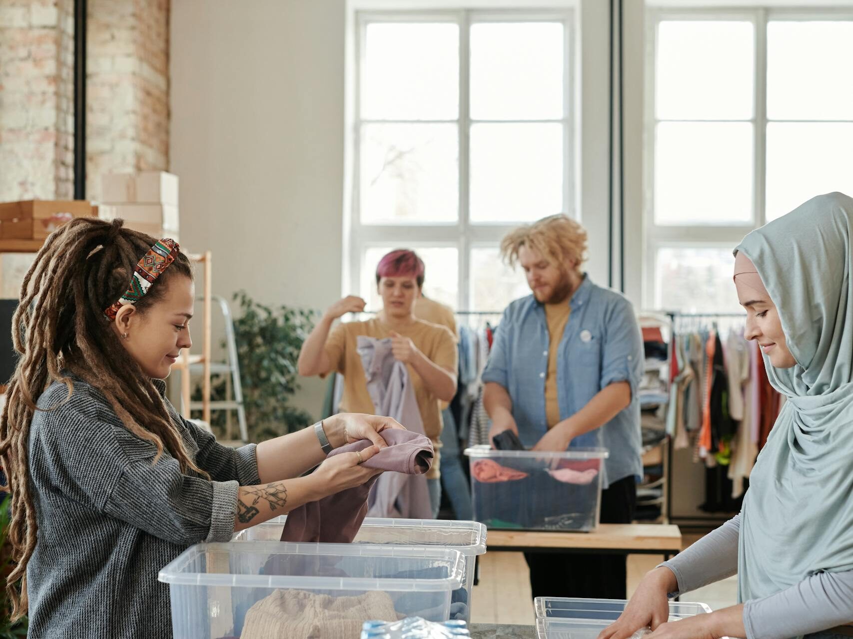 A diverse group of volunteers sorting clothes and food items at an indoor donation center.